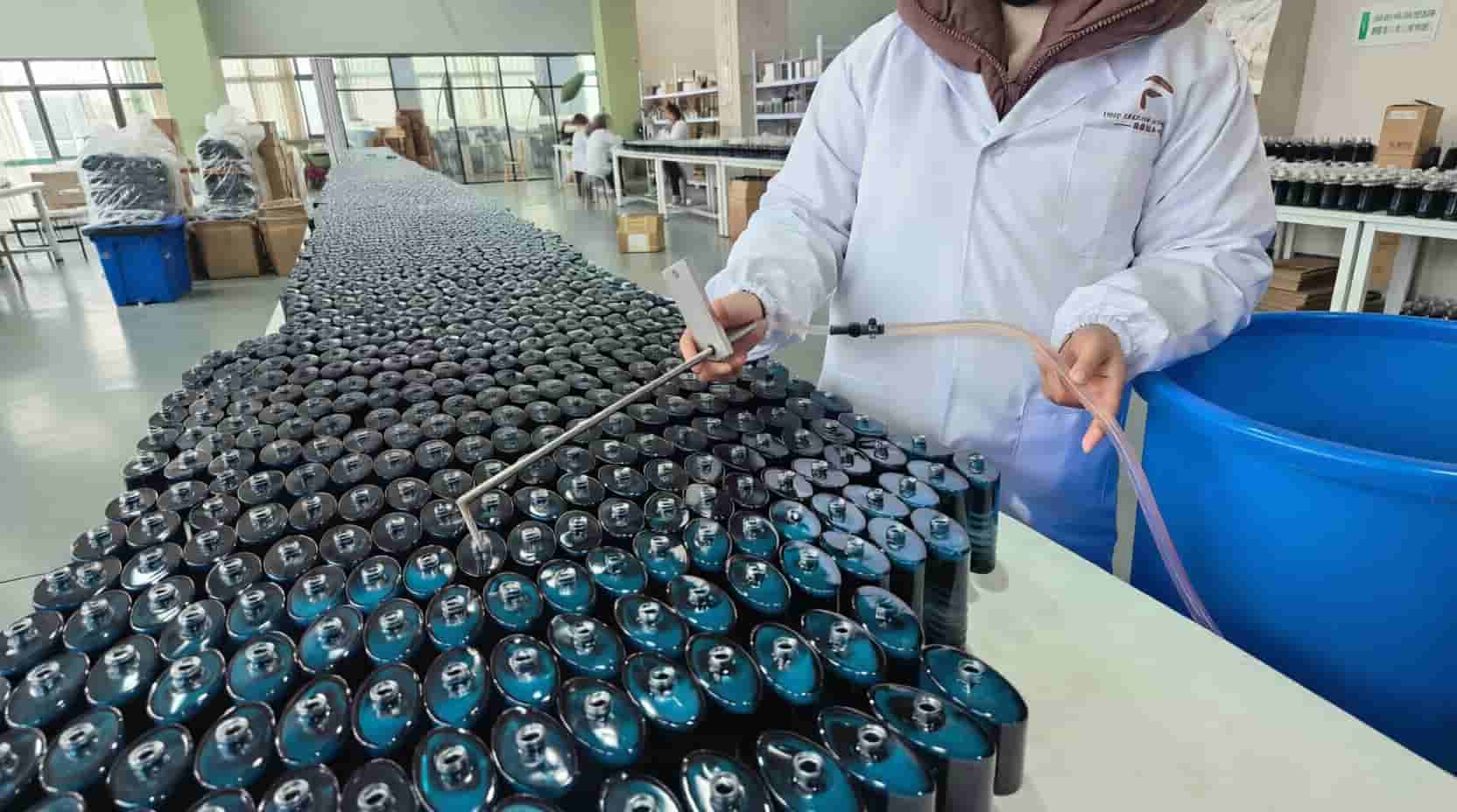 50ml glass perfume bottles lined up on a factory table, representing total manufacturing cost